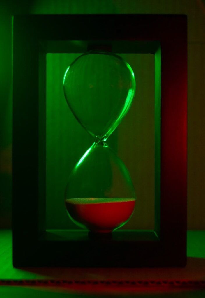 Green-lit hourglass with red sand trickling down.